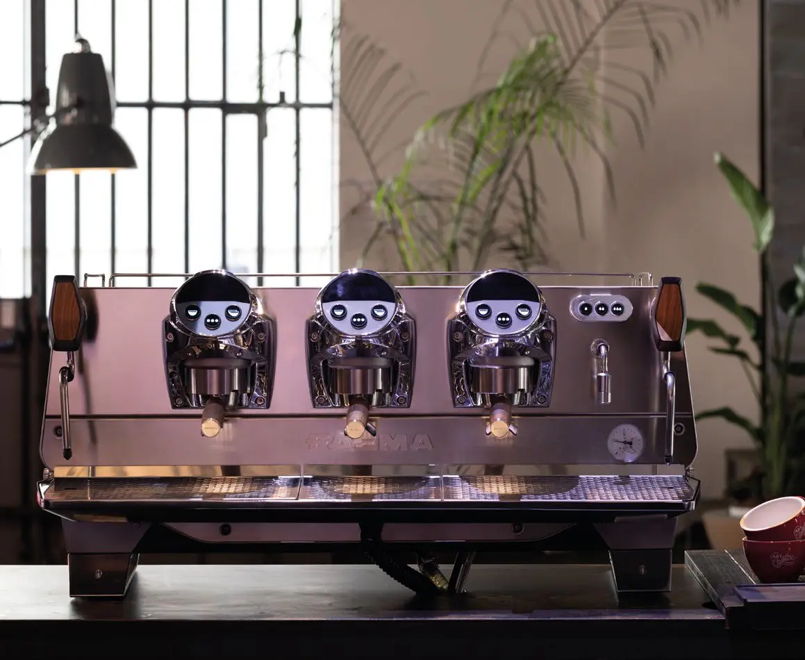 A row of four coffee machines on top of a table.